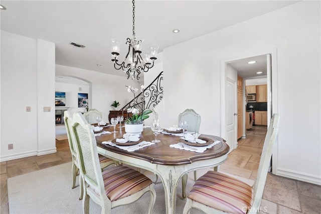 dining room featuring arched walkways, recessed lighting, visible vents, stairway, and a warm lit fireplace