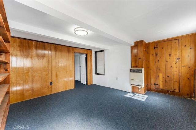 empty room with beam ceiling, carpet flooring, wood walls, and heating unit