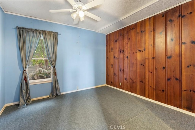 empty room with wood walls, a ceiling fan, and baseboards