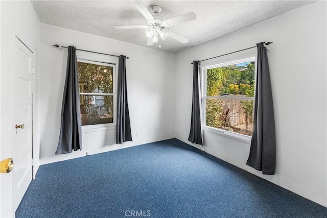 spare room featuring a textured ceiling, carpet floors, and a ceiling fan