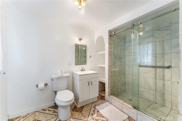 bathroom featuring a stall shower, baseboards, toilet, tile patterned flooring, and vanity