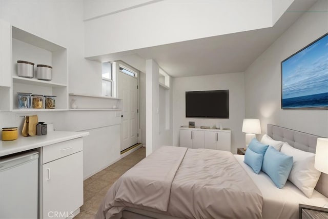 bedroom with light tile patterned floors and fridge