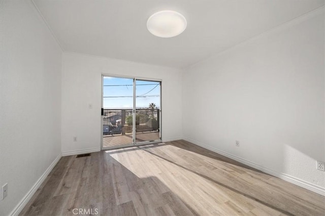 spare room with visible vents, baseboards, and wood finished floors