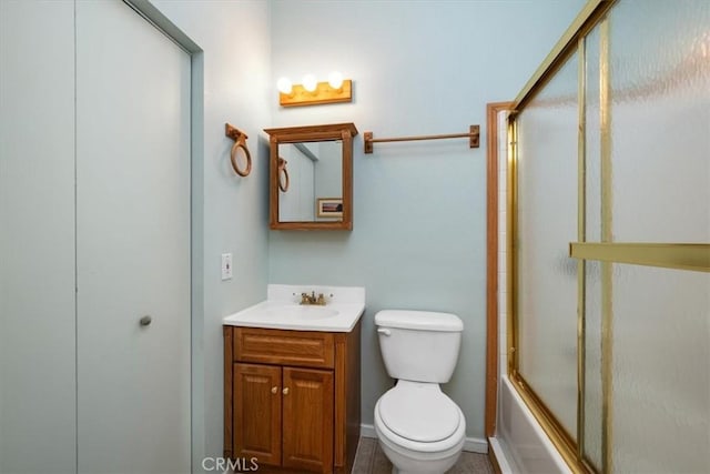 bathroom with toilet, baseboards, vanity, and enclosed tub / shower combo