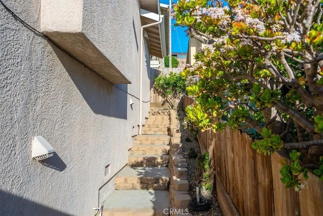 view of side of home with fence and stucco siding