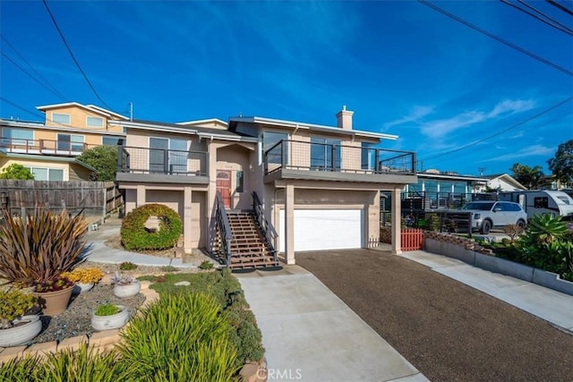 view of front of property with stucco siding, stairway, an attached garage, fence, and a balcony