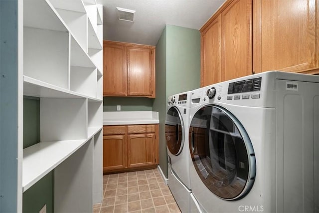 washroom featuring cabinet space, visible vents, washer and clothes dryer, and light tile patterned flooring