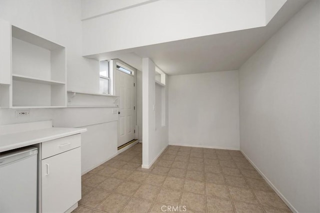 kitchen with dishwashing machine, light countertops, white cabinets, and baseboards