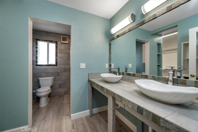 full bathroom with wood finished floors, a sink, toilet, and baseboards