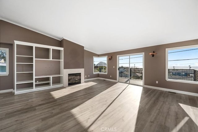 unfurnished living room featuring lofted ceiling, baseboards, a tiled fireplace, and wood finished floors