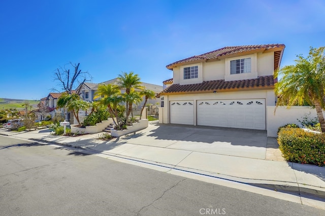 mediterranean / spanish-style house with a garage, concrete driveway, a tiled roof, and stucco siding