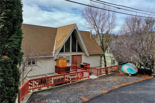 view of front of home with a deck and a shingled roof