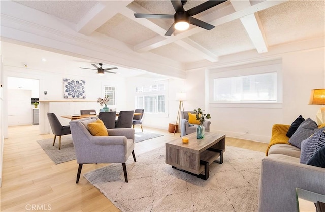 living room featuring ceiling fan, light wood finished floors, beamed ceiling, and coffered ceiling