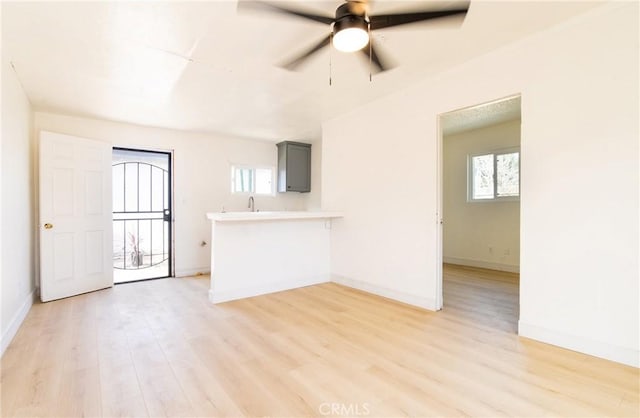 unfurnished room with plenty of natural light, light wood-style flooring, and baseboards