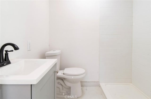 full bath featuring marble finish floor, vanity, a tile shower, and toilet