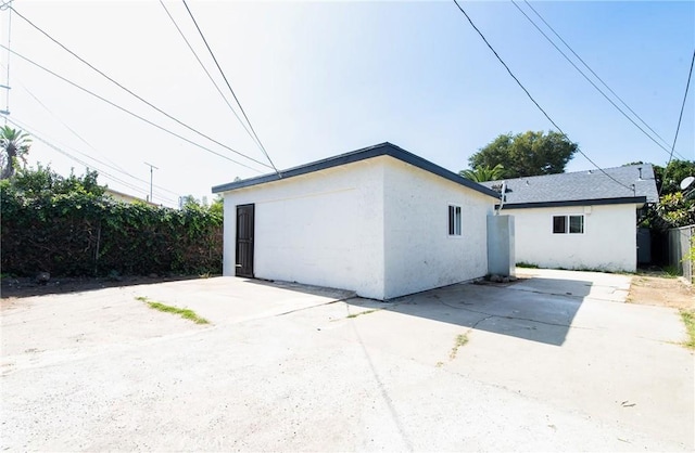 view of side of property featuring a garage, a patio area, fence, and stucco siding