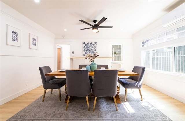 dining space with ceiling fan, light wood finished floors, a wall mounted air conditioner, and baseboards