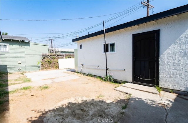 view of property exterior with a patio area, fence, and stucco siding