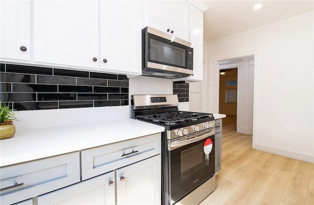 kitchen with tasteful backsplash, stainless steel appliances, crown molding, light countertops, and light wood-type flooring
