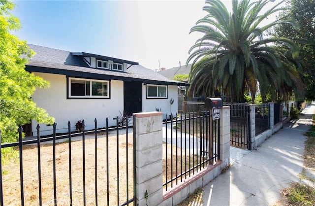 bungalow-style home with roof with shingles, fence, and stucco siding