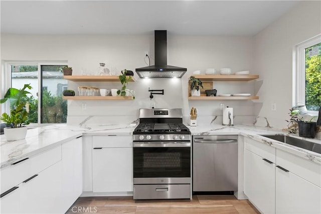 kitchen featuring island range hood, stainless steel appliances, white cabinets, light stone countertops, and open shelves