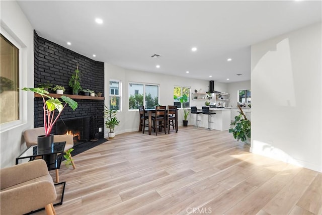 living room with recessed lighting, visible vents, a fireplace, and light wood finished floors