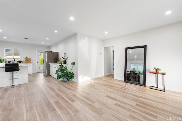 unfurnished living room featuring light wood-type flooring, baseboards, and recessed lighting