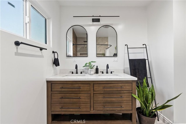 bathroom featuring double vanity, walk in shower, and a sink