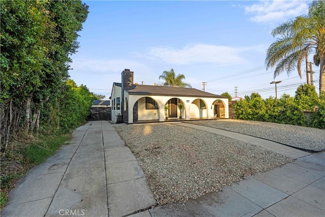 view of front of property with a chimney, concrete driveway, and stucco siding