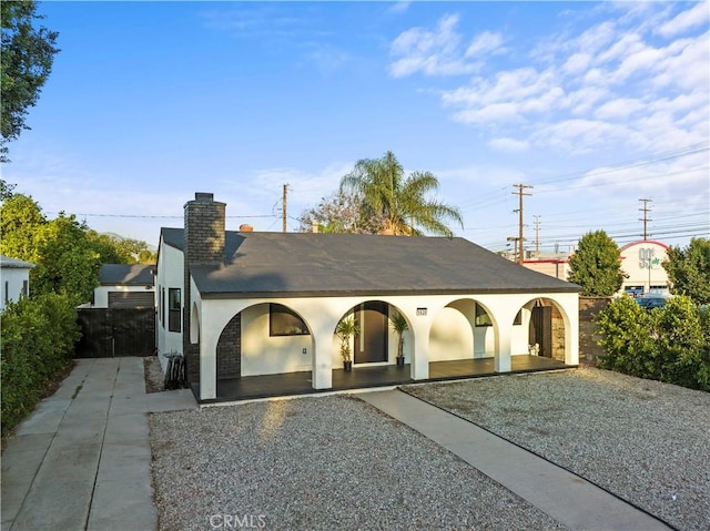 view of front of house featuring a chimney, fence, and stucco siding