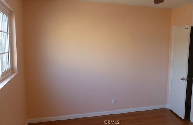 empty room featuring baseboards, a wealth of natural light, and wood finished floors