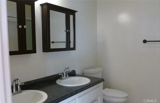 bathroom with double vanity, a sink, and toilet