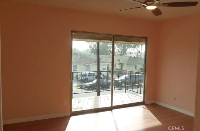 doorway featuring a ceiling fan, a residential view, baseboards, and wood finished floors