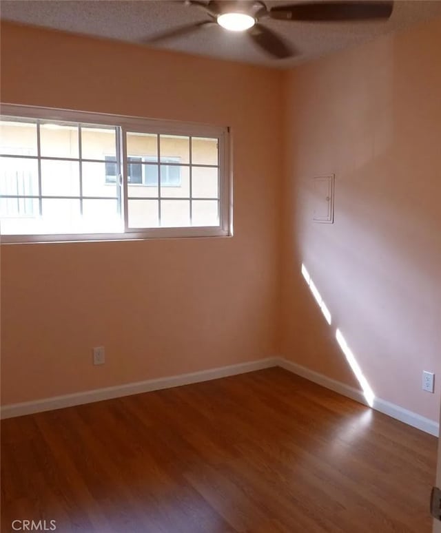 unfurnished room featuring wood finished floors, a ceiling fan, and baseboards