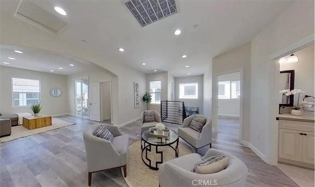 living area featuring light wood finished floors, baseboards, visible vents, arched walkways, and recessed lighting