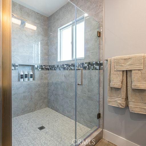 full bathroom with a stall shower and baseboards