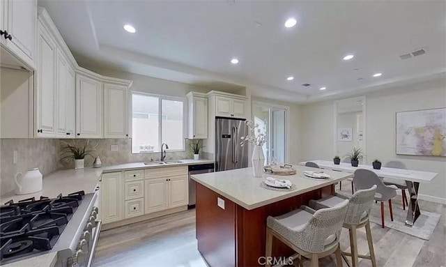 kitchen with stainless steel appliances, light countertops, a kitchen island, and white cabinetry