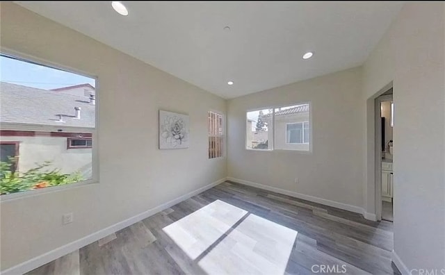 unfurnished room with recessed lighting, wood finished floors, and baseboards