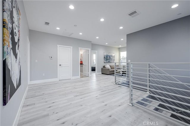 interior space with an upstairs landing, recessed lighting, visible vents, and light wood finished floors