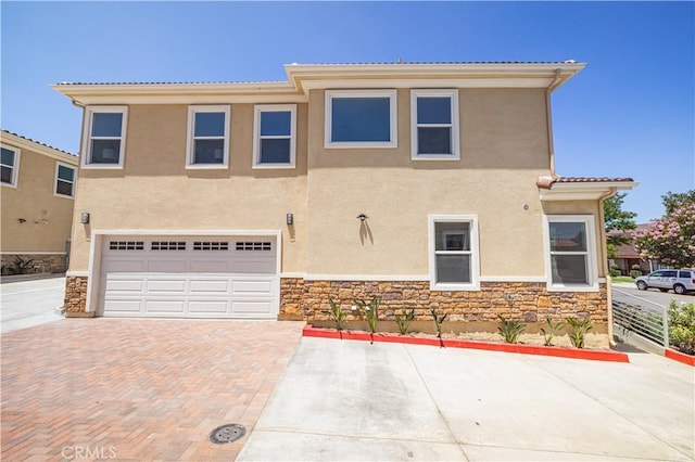 view of front of house with stone siding, decorative driveway, and stucco siding