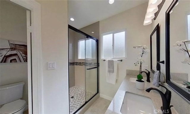 bathroom with double vanity, a stall shower, a sink, and toilet