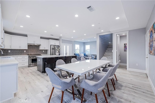 dining area with light wood-style floors, recessed lighting, visible vents, and stairs