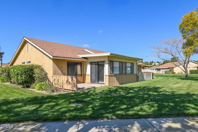 view of front of home featuring roof with shingles, fence, a front lawn, and stucco siding