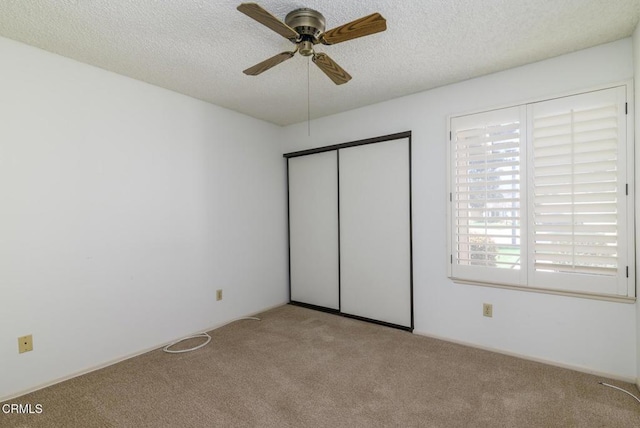 unfurnished bedroom with a ceiling fan, carpet, a closet, and a textured ceiling