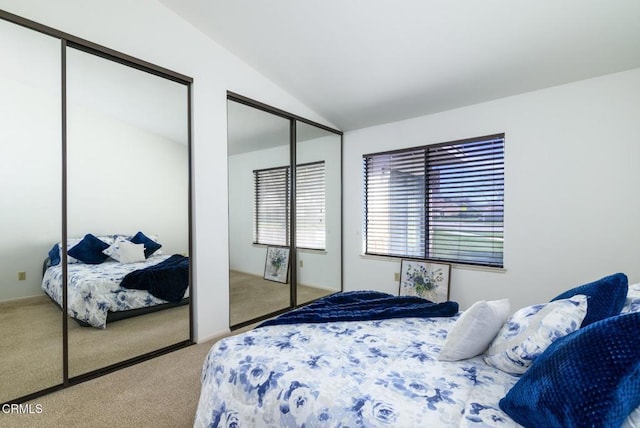 bedroom featuring carpet, vaulted ceiling, and two closets