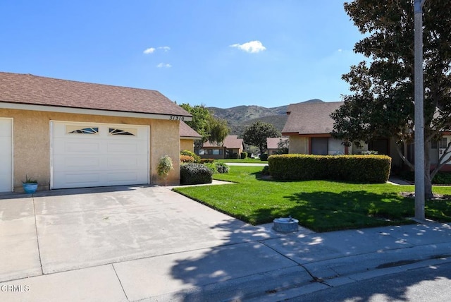 view of property exterior with a garage, driveway, a yard, a mountain view, and stucco siding