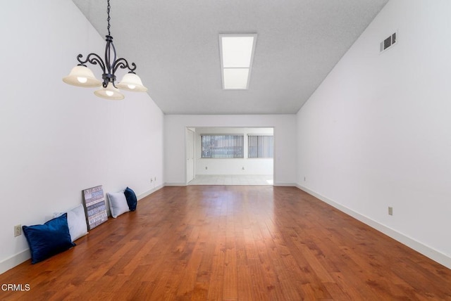 interior space with a notable chandelier, wood finished floors, visible vents, and baseboards