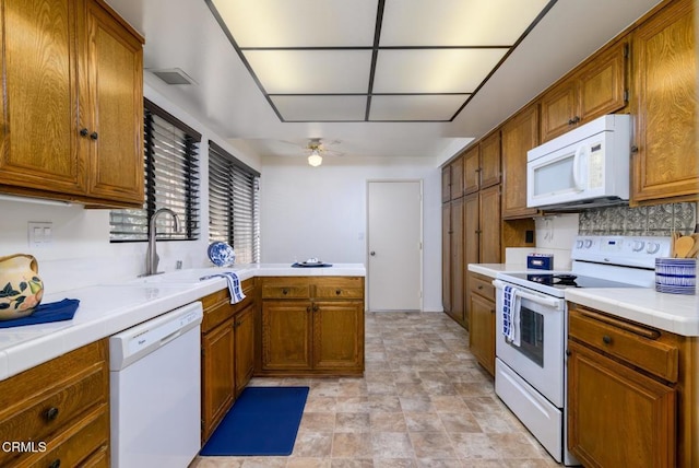 kitchen featuring tile countertops, white appliances, brown cabinetry, and a sink