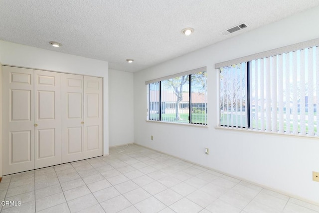 unfurnished bedroom featuring a textured ceiling, visible vents, and a closet