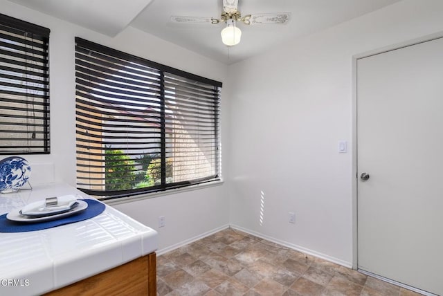 office area with ceiling fan, stone finish floor, and baseboards